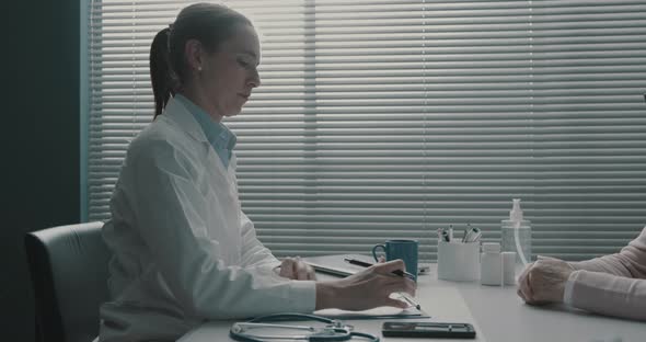 Doctor writing a medical prescription for a senior patient