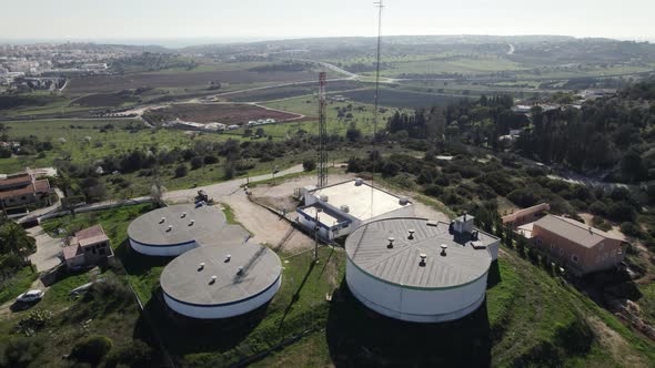 Aerial orbiting industrial Water storage tanks on top of hill, Portuguese countryside. Algarve