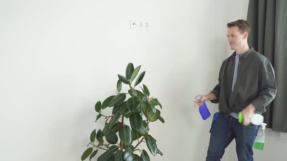Man Spraying Water on House Plant Flower with Spray Bottle at Home
