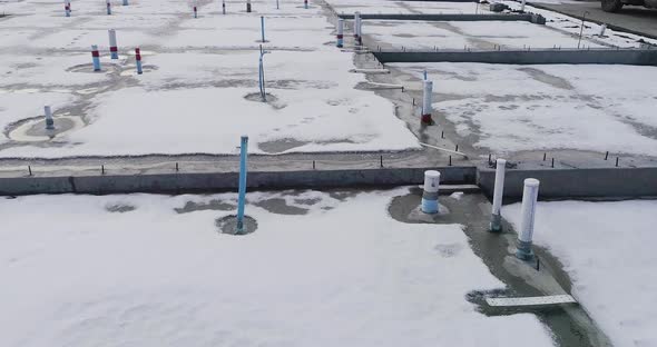 A concrete foundation is fully stubbed out for utilities. Snow on the ground. alt