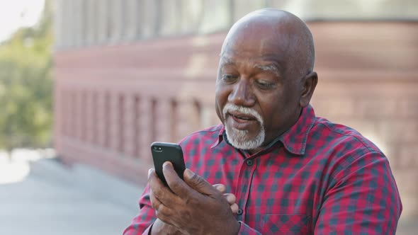 Kind Calm Senior Black Grandfather Makes Video Call Looks at Smartphone Camera African American alt