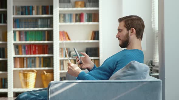 Young male typing on smartphone at home office alt