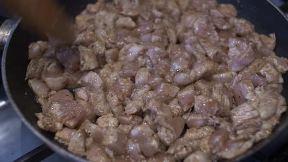 Wooden Spoon Stirring Diced Chicken Pieces In Hot Pan. Locked Off alt