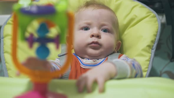 Little Boy Tries To Take Bright Toy Sitting in Highchair alt