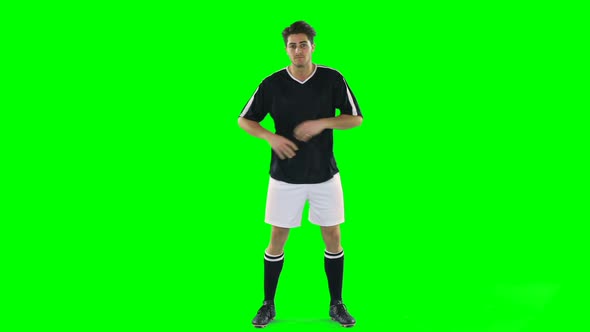 Confident football player standing against green screen alt
