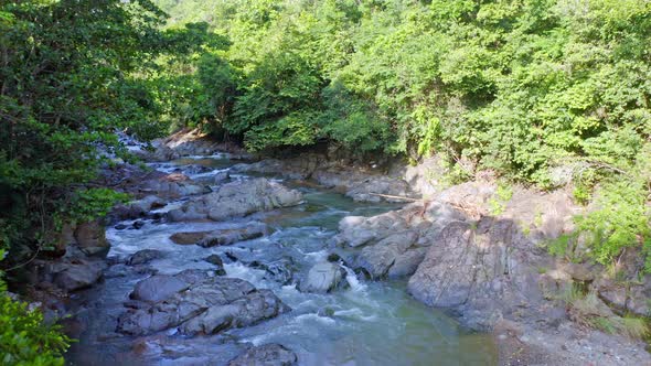 Water Higuero stream flowing between rocks in untouched nature, La Cuaba. Aerial drone low altitude alt