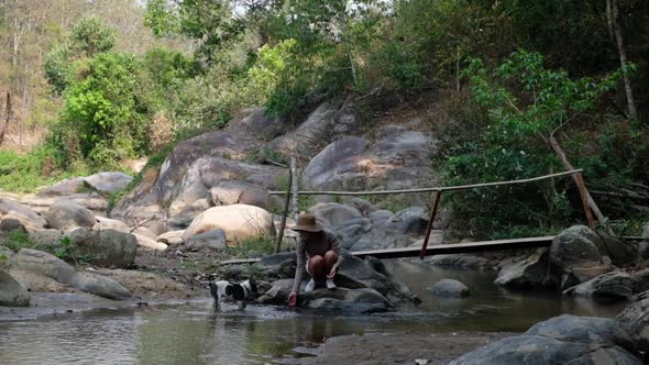 Slow motion of a young woman playing with water and a dog by the waterfall