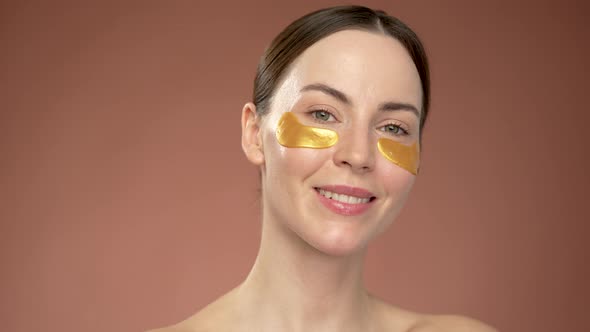 Woman Applying Eye Patches on Brown Background