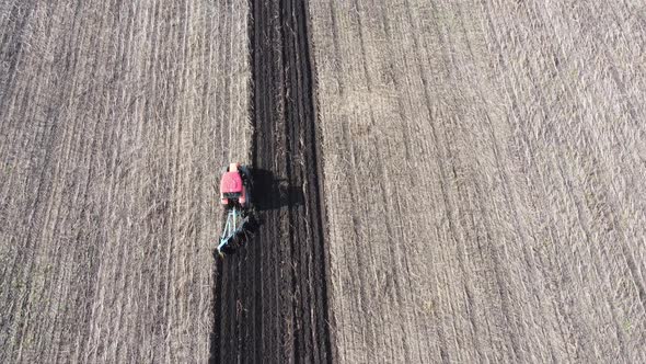 Shooting From Drone Flying Over Tractor with Harrow System Plowing Ground on Cultivated Farm Field