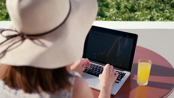 Woman in Hat Works on Laptop in Hotel with Sea View in Summer Sunny Day