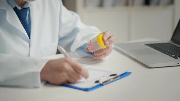 Close Portrait of Elderly Doctor Examining Medicine and Writing Notes alt