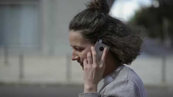 Attractive Mature Lady Walking on City Street with Smartphone alt