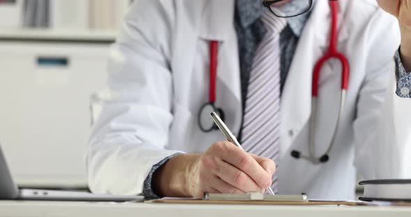 Doctor Sitting at Table and Filling Out Medical History with Pen  Movie alt