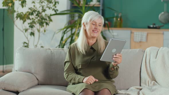Happy Elderly Woman Makes an Online Call Using Her Tablet Online Chatting alt