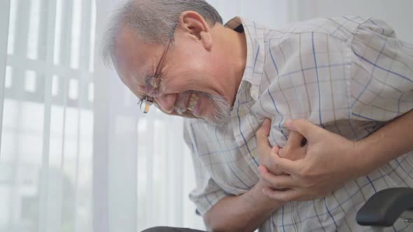 Asian senior man suffering from heart attack on wheelchair