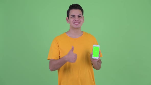 Happy Young Multi Ethnic Man Showing Phone and Giving Thumbs Up alt