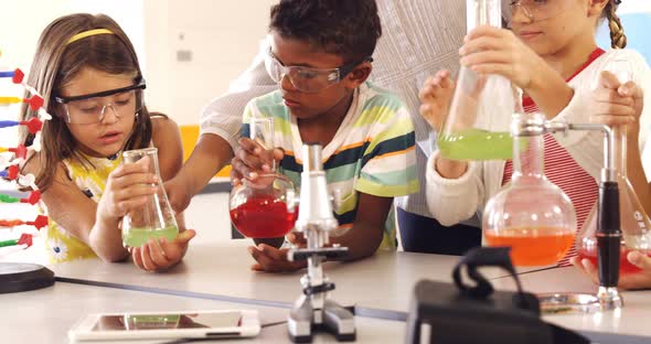 School kids doing a chemical experiment in laboratory alt