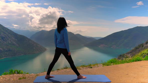 Taut Woman Practicing Yoga Exercises on Mountain Top alt