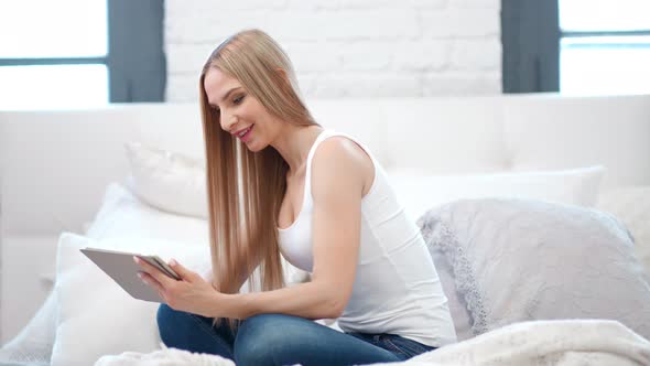 Sexy European Woman Sitting on Bed in Bedroom Using Tablet Pc Full Shot alt