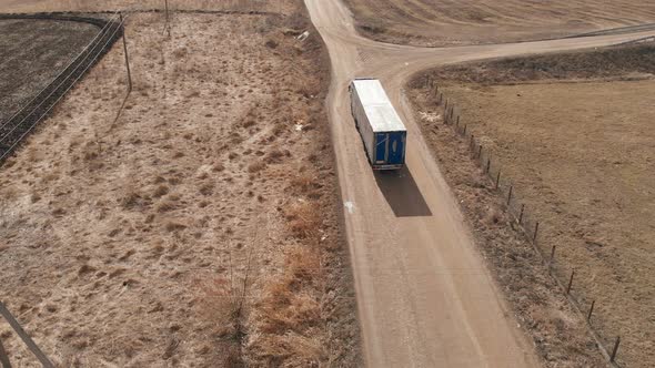 Aerial View of a Large Truck with a Trailer Driving Along a Dirt Road in Search of a Place alt