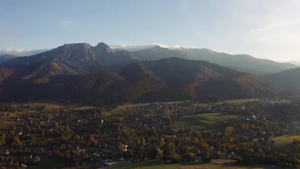 Aerial View Flight Over Mountain Village Lit with Warm Sunlight alt