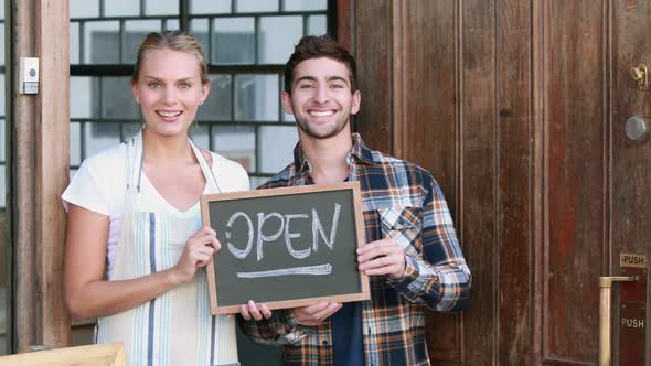 Smiling Waitress and Hipster Man Holding Open Sign Board alt