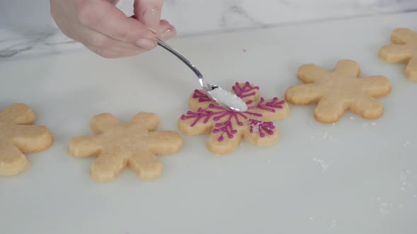 Step by step. Icing snowflake shaped sugar cookies with pink royal icing. alt
