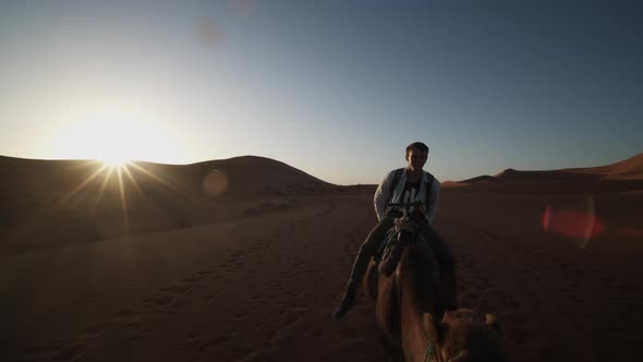 View of Mid Adult Man Riding on Camel in Desert alt