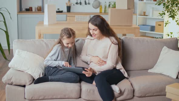 A Pregnant Woman with a Child Makes Online Purchases Using a Computer alt