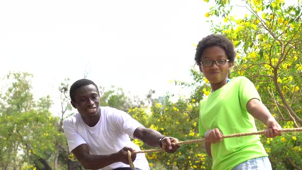 African American Father and Daughter Pulling a Rope Together in Tug of War Competition alt