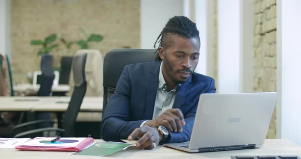 Portrait of Successful Young African American Businessman Looking at Laptop and Making Victory alt