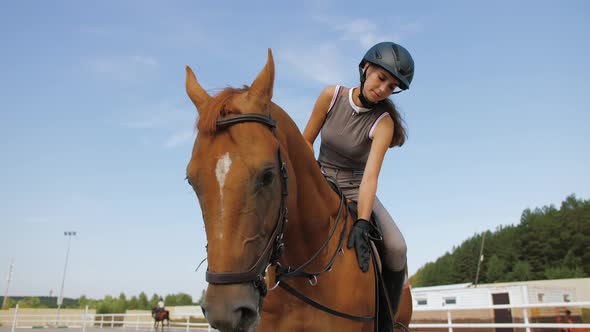 Female Jockey Horseback Caresses Brown Horse Rider Stroking and Hugging Horse alt