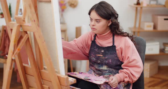 Front View of Concentrated Beautiful Girl with Genetic Disorder Painting in Her Room alt