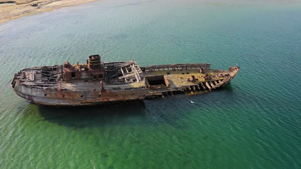 A Wrecked Wooden Ship Lies on the Seashore Covered with Rust alt