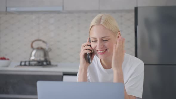 Attractive Blonde Woman is Excited and Laughs During Phone Call at Home