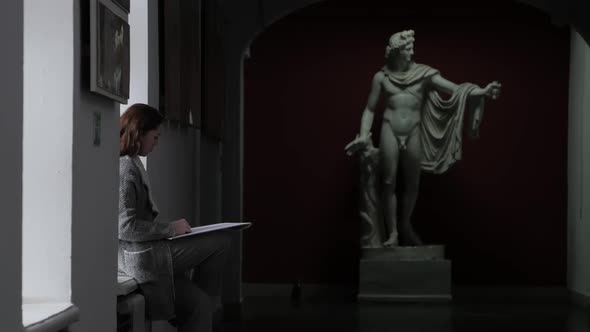 A Young Girl Artist Draws an Antique Sculpture of a Man in the Corridor of the University Sitting on
