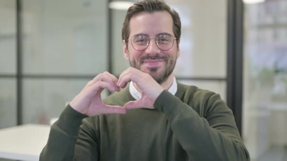 Portrait of Young Businessman Showing Heart Shape By Hands alt