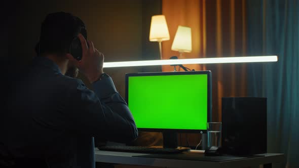 Concentrated Young Man in Headphones with Computer Working at Home Office alt