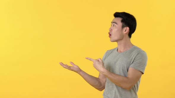 Portrait of a young asian man getting surprised and excited with hand open