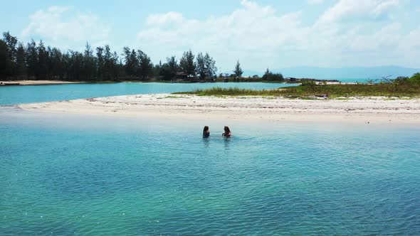 Beautiful ladies happy and smiling on idyllic island beach holiday by blue lagoon with white sand ba alt