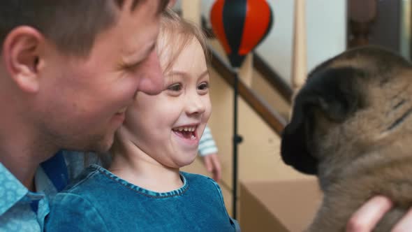 Laughing dad and girl sitting face to face with puppy