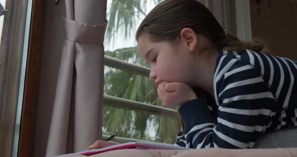 A Pre-school Girl Drawing with Pencils at Home