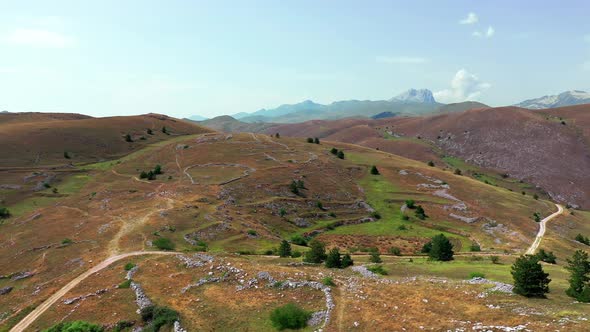 Aerial View of Arid Country Land Some Green Bushes and Trees Blue Sky Mountain in the Horizon Dirty alt