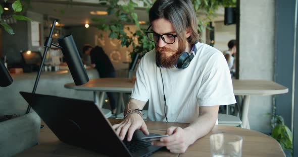 Man Paying with Credit Card on Laptop in Cafe