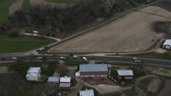 View of farm land and rural highway with rescue vehicles at scene of accident in a valley.