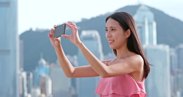 Woman taking photo on cellphone in Hong Kong alt