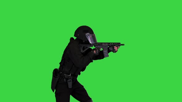 Policeman in Black Camouflage Walking and Shooting From the Machine Gun on a Green Screen Chroma Key alt