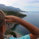 Boy Traveller with Arm Raised on Top of Mountain Looking at View of Adriatic Sea and Rocky Mountains