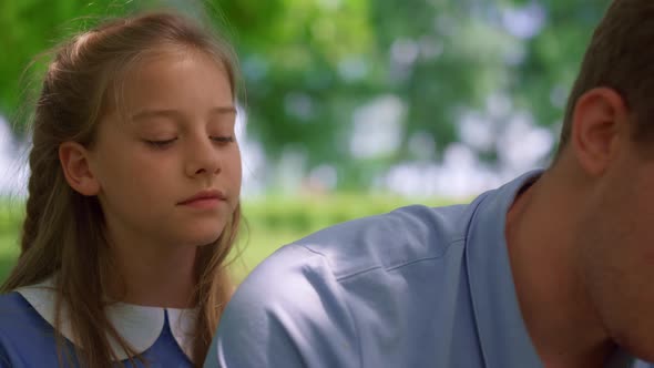 Girl Sitting Near Father on Lawn Close Up alt