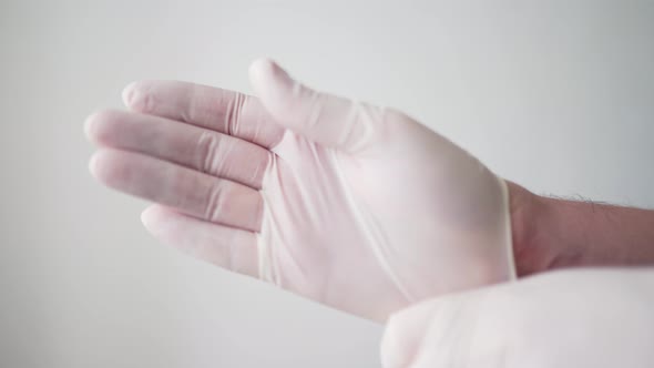 The Doctor Puts White Protective Gloves on His Hands. A Professional Medical Worker. Pandemic